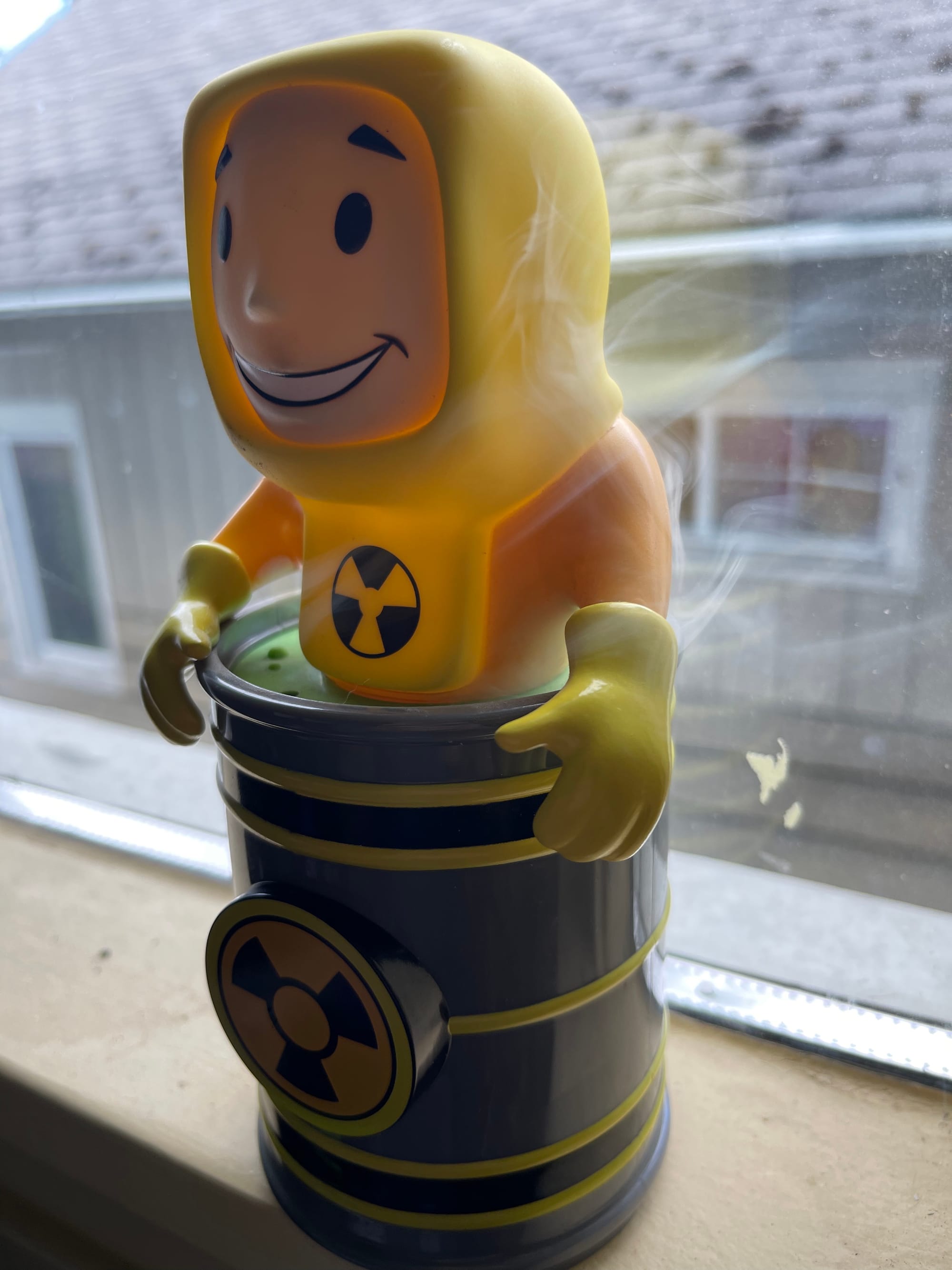 A Vault Boy incense burner, as described previously, with smoke wafting out of the vents on the barrel.